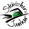 Flasche Junker 2025 vom Weingut Gründl mit Steirerhut, umgeben von herbstlichen Farben – frischer Jungwein aus der Südsteiermark. 💚⭐